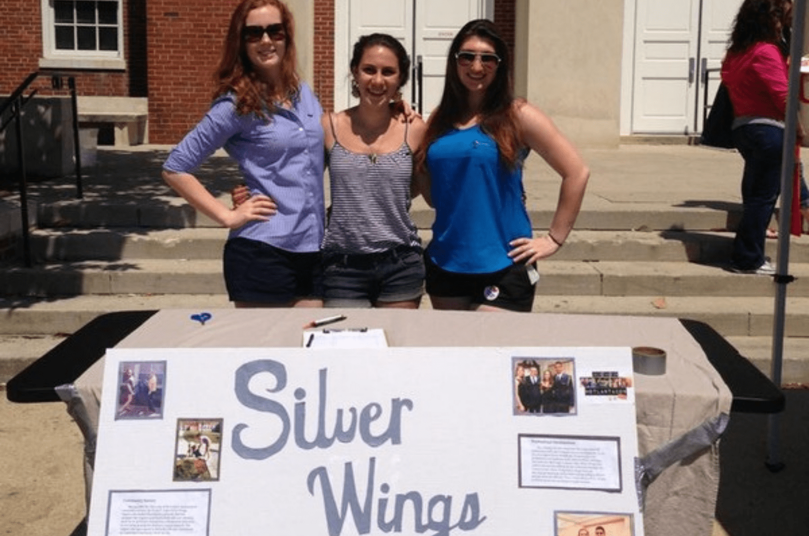 three students in front of silver wings poster
